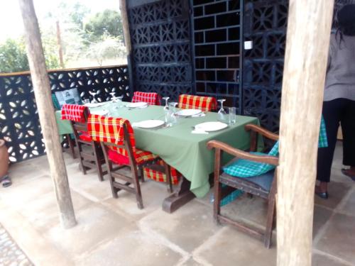 a table with red chairs and a green table and chairsktop at Ndege Mingi Bush Camp - Laikipia in Nanyuki