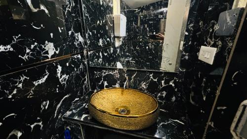 a bathroom with a gold sink on a black wall at Hidden heritage ins in Ooty