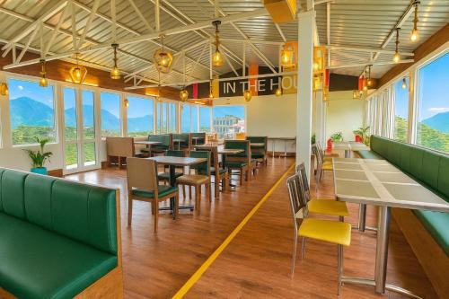 a restaurant with tables and chairs and mountains in the background at The Kempty Osasis - A Boutique Resort With Scenic Mountain View in Mussoorie in Mussoorie