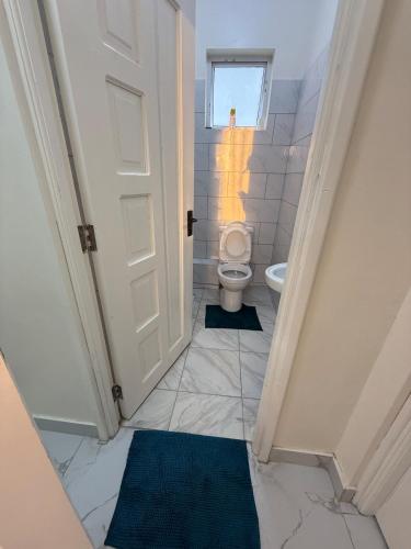 a bathroom with a toilet and a window at Waridi is a modern, cosy penthouse in Mtwapa town in Mtwapa