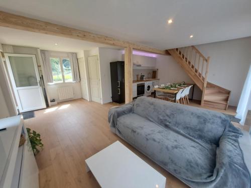 ein Wohnzimmer mit einer blauen Couch und einer Küche in der Unterkunft Chalet Bois 6 personnes Sauna et Gym in Bellecombe