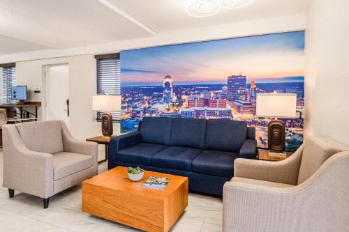 a living room with a blue couch and a large window at Clarion Pointe Winston - Salem Downtown in Winston-Salem