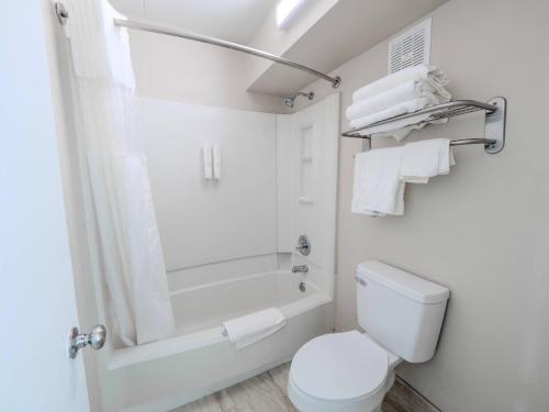 een witte badkamer met toilet en douche bij Clarion Pointe Winston - Salem Downtown in Winston-Salem