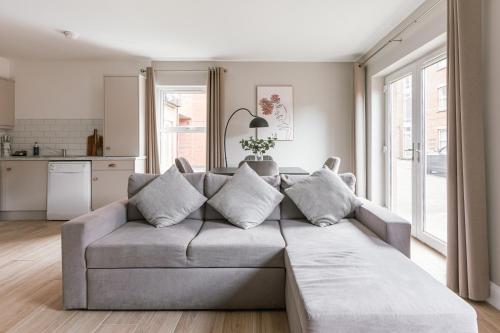 a living room with a gray couch and a kitchen at Luxurious 2 Bedroom City Centre Apartment Walking Distance to Everything Sleeps 6 in Belfast