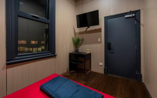 a room with a door and a window and a tv at Capsule Hostel Perth - note - Valid passport required to check-in in Perth