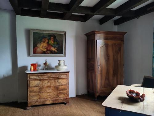 une chambre avec un tableau sur le mur et une commode en bois dans l'établissement L'envol, à Germond