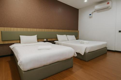 a room with two beds and a air conditioner at Watermelon Hotel in Miri