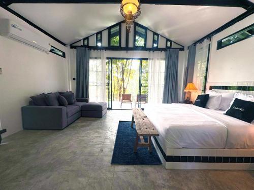 a bedroom with a large bed and a couch at Barefoot Project formerly Baan Klong Kleng in Ko Phayam
