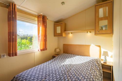 a bedroom with a bed and a window at Mobil Home 40 M², Proche De La Mer in Saint-Nazaire-sur-Charente