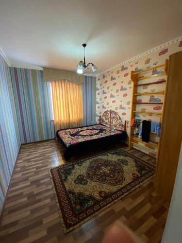 ein Schlafzimmer mit einem Bett und einem Teppich in der Unterkunft Гостевой дом с 7 комнатами in Schymkent