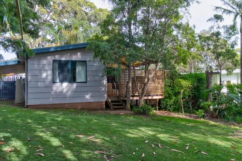 a tiny house with a porch and a yard at Lockhart Leafy Cottage - walk to Mollymook Beach in Mollymook