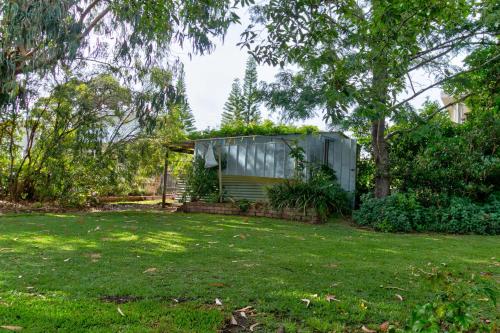 a house with a greenhouse in a yard at Lockhart Leafy Cottage - walk to Mollymook Beach in Mollymook