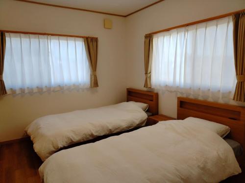 two beds in a room with two windows at Maison West Building B - Vacation STAY 18462 in Shimo-nogami