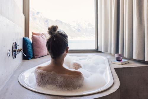 a woman sitting in a bath tub looking out a window at Seehotel Einwaller - adults only in Pertisau