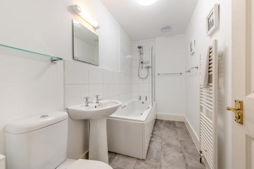 a white bathroom with a sink and a toilet at Francis Cottage in Woolacombe