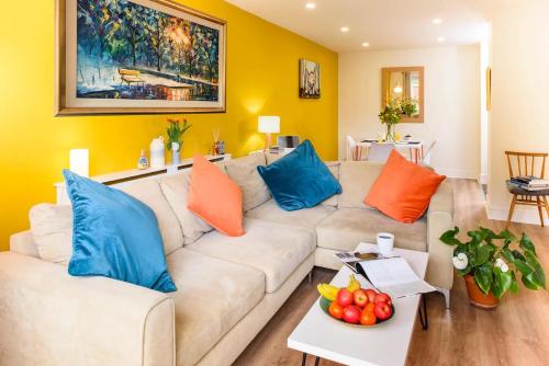 a living room with a white couch with blue and orange pillows at Luxury City Apartment Underground Parking 5* in Belfast