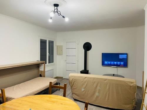 Zimmer mit einem Tisch und einem TV an der Wand in der Unterkunft Appartement fonctionnel in Malleval