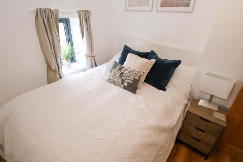ein Schlafzimmer mit einem weißen Bett mit Kissen und einem Fenster in der Unterkunft Rose Cottage in Killala
