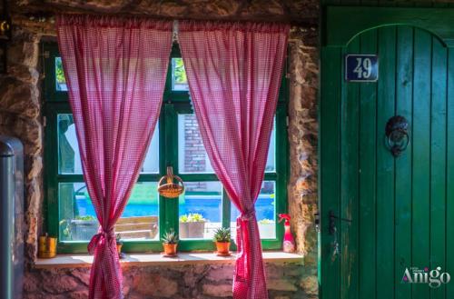 a window with red curtains and a green door at Villa Kamenjarka in Široki Brijeg