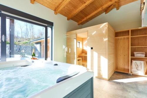 a large bath tub in a room with a large window at Family friendly house with a swimming pool Karlovac - 22371 in Karlovac