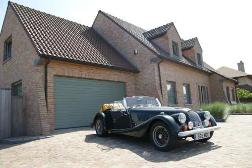 an old car parked in front of a garage at B&B The Beachhouse in Oostduinkerke