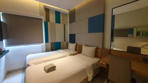 een hotelkamer met twee bedden en een spiegel bij IXO Hotel Semarang in Stasiun Tawang