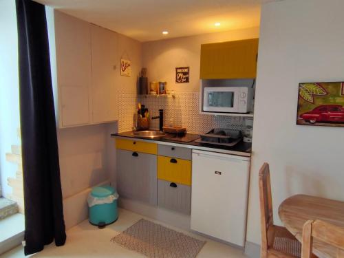 une petite cuisine avec un évier et un micro-ondes dans l'établissement Logement de Charme en centre ville, à Lesneven