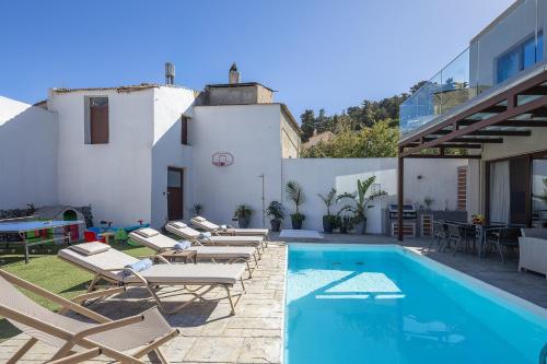 a pool with chaise lounge chairs next to a building at Villa Fotinou Heated Pool & Free Bikes awaits in Fotinós