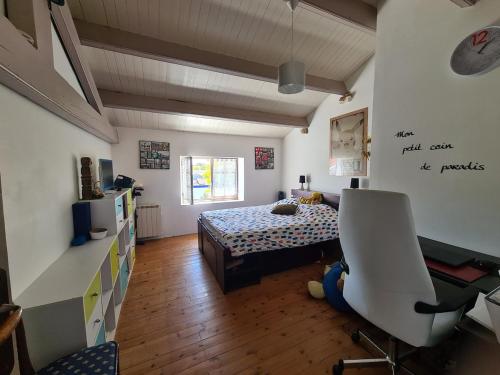 a bedroom with a bed and a desk and a chair at Maison sur Ile de Noirmoutier in LʼÉpine