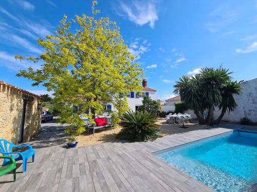 a backyard with a swimming pool and a tree at Maison sur Ile de Noirmoutier in LʼÉpine