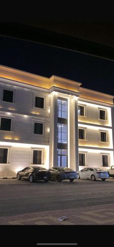 a large white building with cars parked in front of it at شقق المصيف الفندقيه in Hafr Al Baten