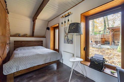 a bedroom in a tiny house with a bed and a window at Bohém Kabin & Wellness in Kismaros