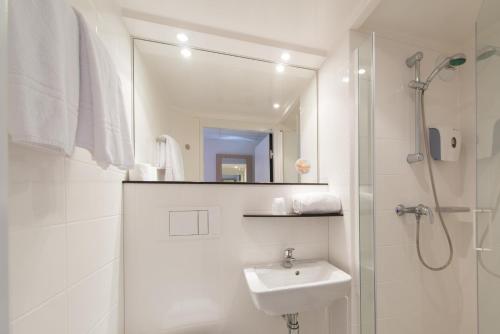 ein weißes Bad mit einem Waschbecken und einer Dusche in der Unterkunft Première Classe La Rochelle Centre - Les Minimes in La Rochelle