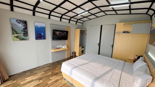 a bedroom with a white bed in a room with windows at The Lakebox Menjer by Travelink in Garung