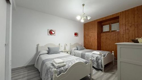 two beds in a room with white walls and wood at CASA DEL VIDRIO in Castril