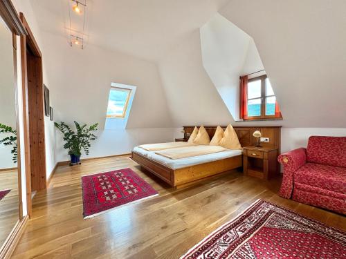 um quarto com uma cama e uma cadeira vermelha em Gästehaus Turm Wachau em Weissenkirchen in der Wachau