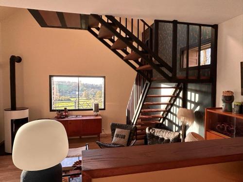 a living room with a staircase with chairs and a table at Gîtes et Spa en Normandie in Sainte-Marguerite-de-Viette