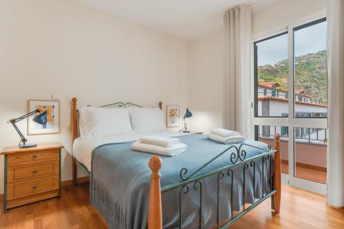a bedroom with a bed and a large window at Ribeira brava - duplex sea view in Ribeira Brava