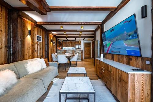 een woonkamer met een bank en een flatscreen-tv bij Luxury suite 70m2 balcon courchevel1850 parking in Courchevel