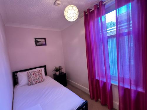 a bedroom with a bed and a window with pink curtains at Private Rooms in Portsmouth in Portsmouth