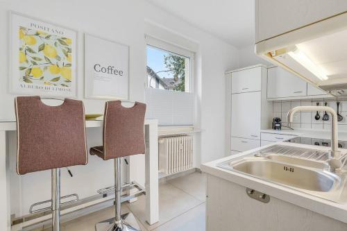 a white kitchen with a sink and two chairs at Moderne Traumwohnung mit Traumgarten in Mayen