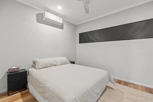 a white bedroom with a bed and a large window at Broome Villa Oasis in Broome