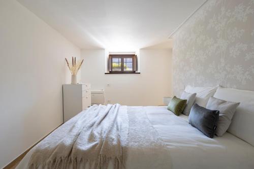 une chambre blanche avec un grand lit blanc avec des oreillers dans l'établissement Maison Carola Sous Les Étoiles, à Aoste