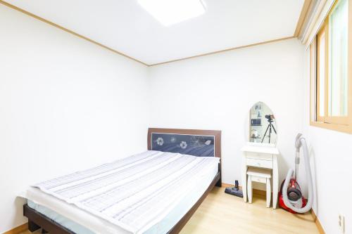 a white bedroom with a bed and a vacuum at 온담펜션 