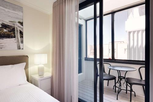 a bedroom with a bed and a table and a balcony at Queen Bed with Balcony at Manly - 3min walk to Corso & Manly Beach in Sydney