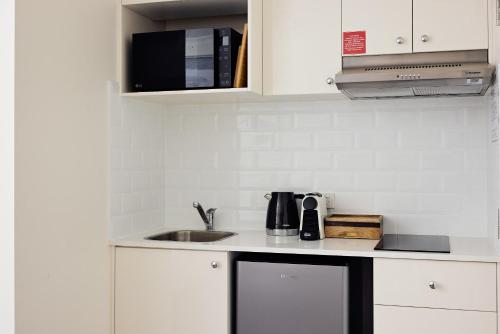a white kitchen with a sink and a microwave at Queen Bed with Balcony at Manly - 3min walk to Corso & Manly Beach in Sydney
