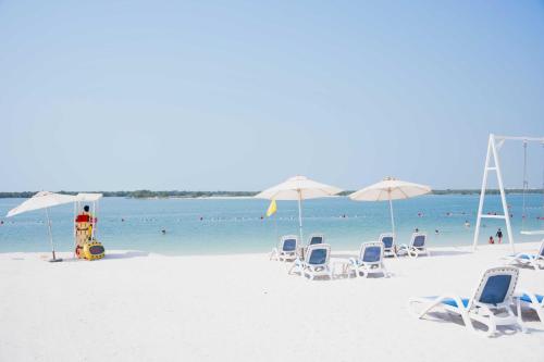 a group of chairs and umbrellas on a beach at Luxury Jr. 1BR in Mayan Yas Island in Abu Dhabi
