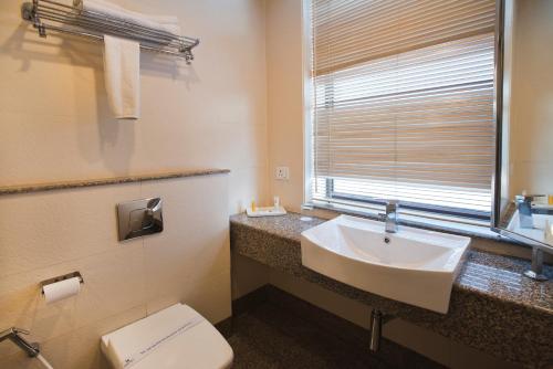baño con lavabo y aseo y ventana en The Manor Bareilly by Leisure Hotels, en Bareilly