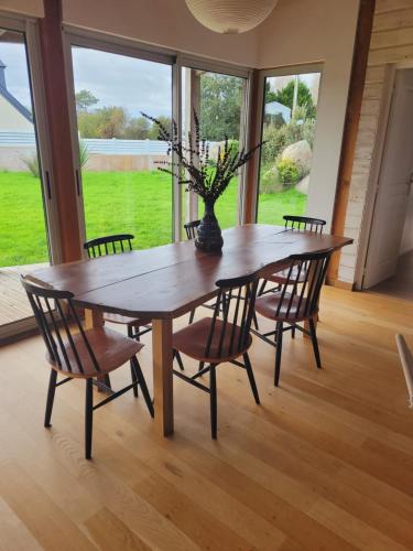 a dining room table with chairs and a large window at Maison moderne, ambiance californienne, proche mer in Plouescat