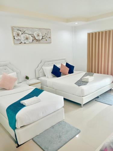 two beds in a white room with blue and pink pillows at Dream Homestay Hat Yai in Sathani Khlong Rian